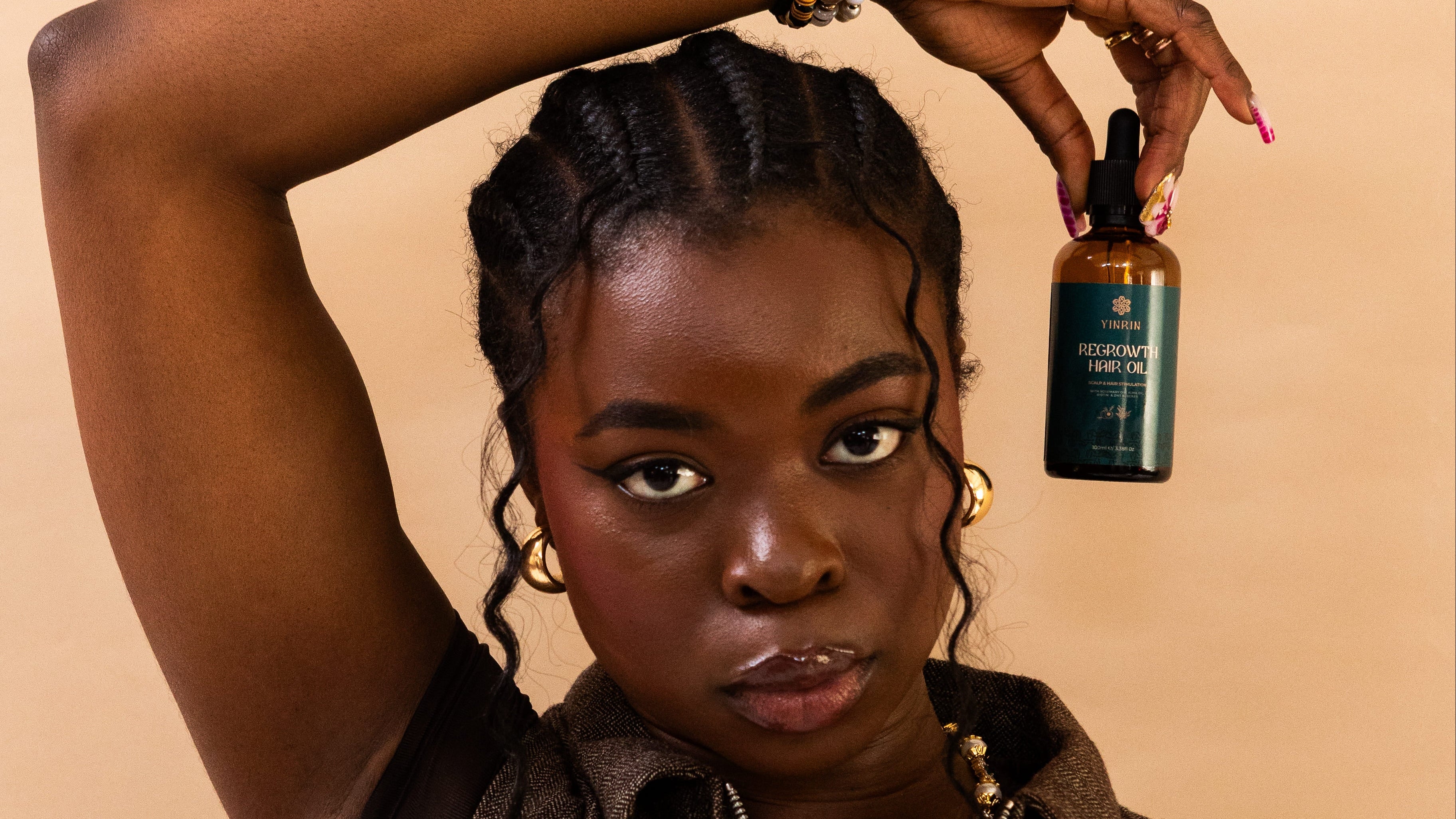 Woman holding a bottle of hair product against a beige background