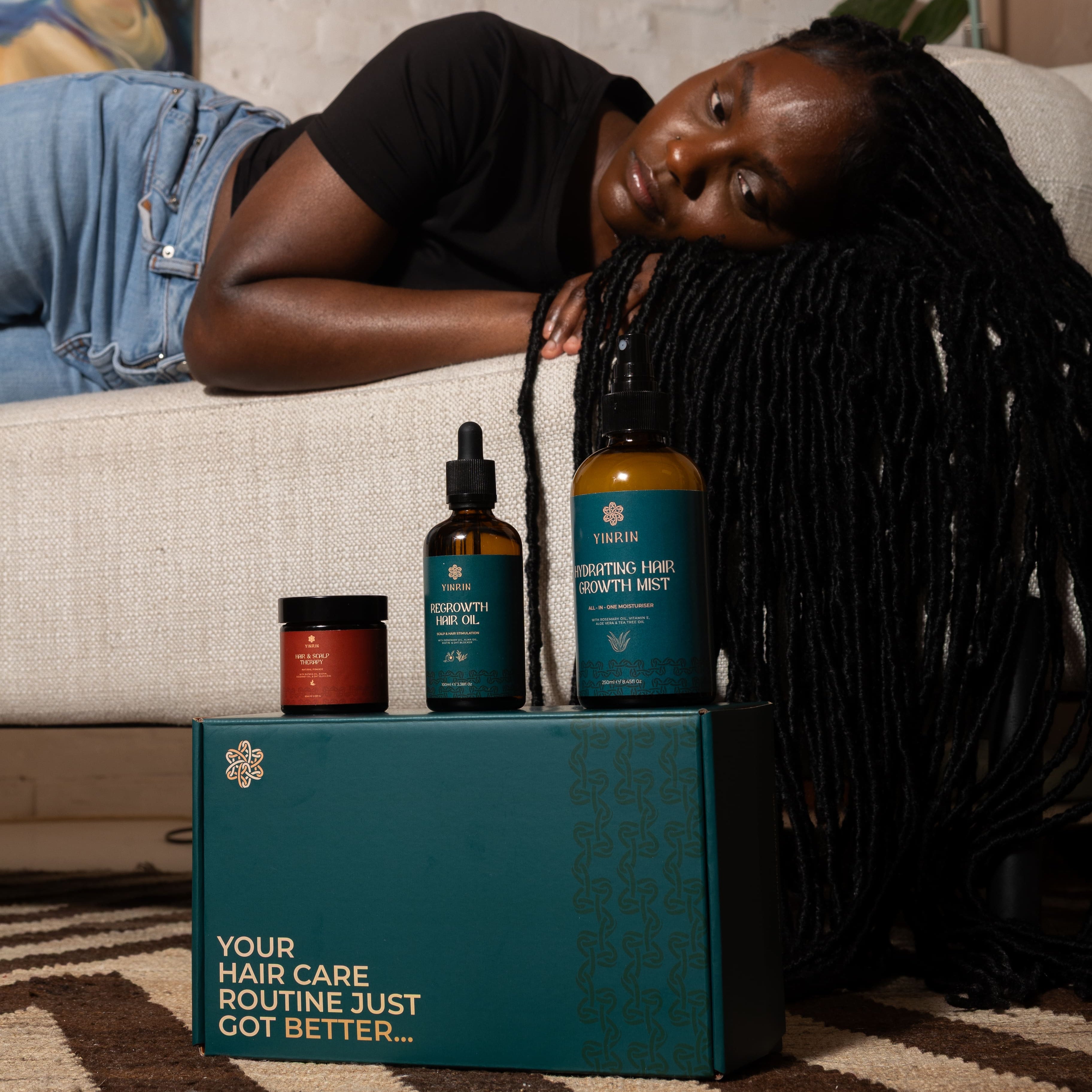 Woman lying on a couch with hair care products in front of her