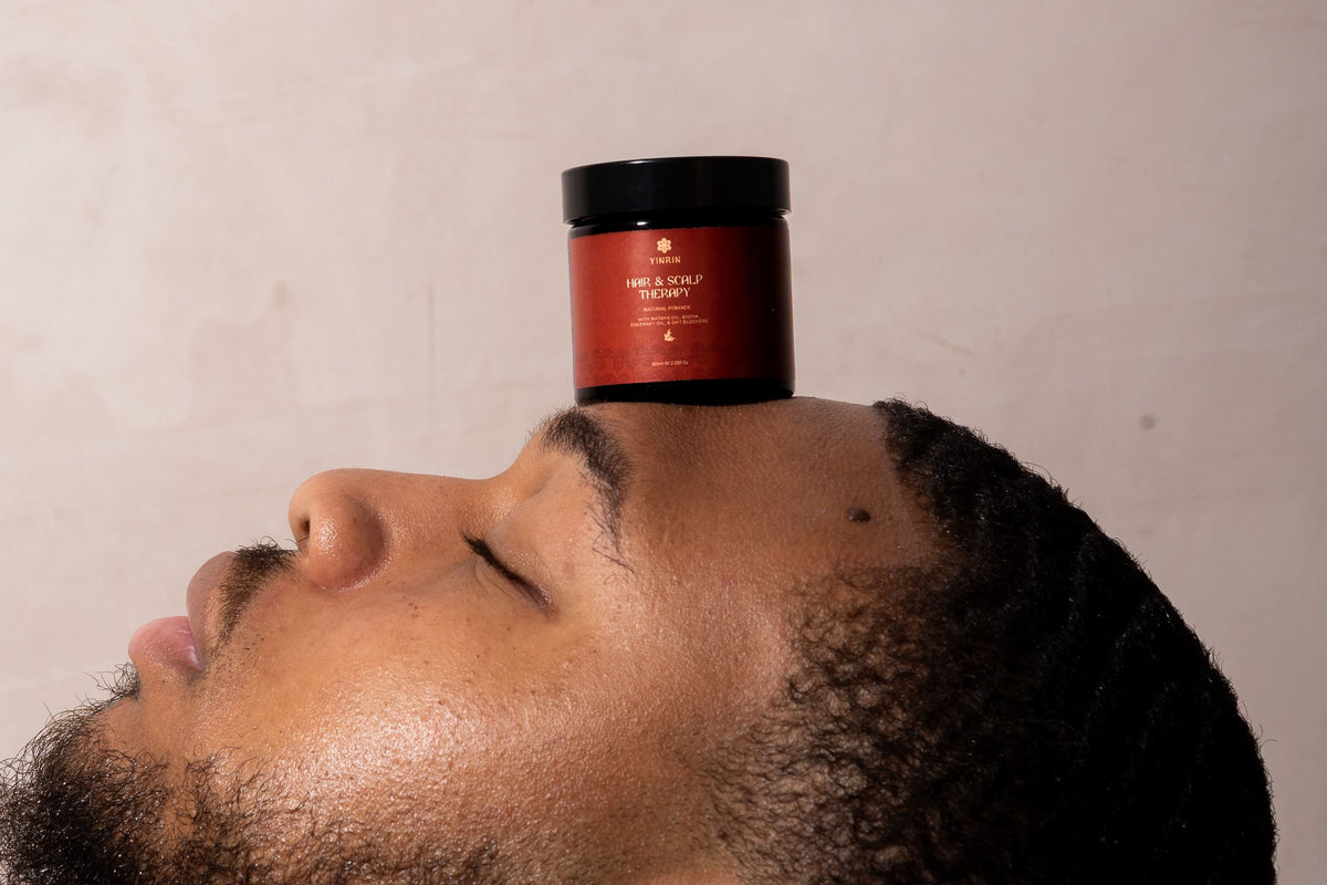 Person balancing a red container on their head against a plain background